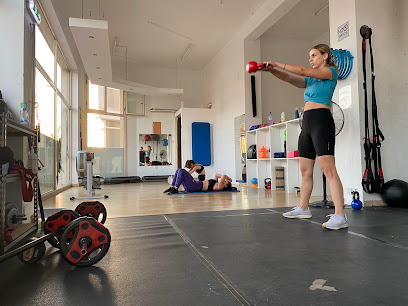 A trainer coaching a kettlebell exercise on the studio floor at RnB Fitness Studio